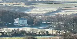 a large house in landscape of fields and trees