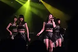 Four women in matching outfits under stage lights