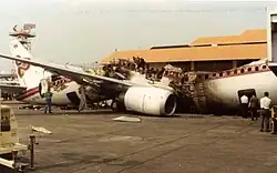 A burnt-out Boeing 737 resting on the ground with a purple cheatline