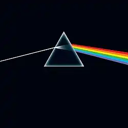 A prism refracting white light into a rainbow on a black background