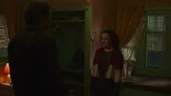 Standing in a bedroom at night, Ellie looks upset at Joel.