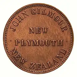 The obverse of a copper penny token, featuring the text "NEW PLYMOUTH", arcing above "JOHN GILMOUR" and below "NEW ZEALAND"