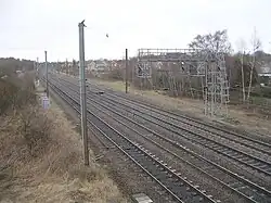 An electrified railway line with housing beyond