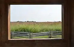 The central attraction of the Battle of Island Mound State Historic Site is its viewing station, which contains several informational signs and offers this framed view of the site and a split rail fence.