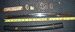 An antique Japanese wakizashi with koshirae and related parts, shown dis-assembled. The hamon (temper line) is clearly visible.