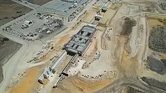 Drone shot of a sandy construction site with concrete retaining walls and bridges