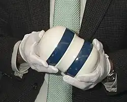 Blue and white dumbbell shaped device, held in gloved hands