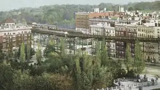 Postcard depicting a forest in Morningside Park with an IRT station and high-rise buildings in the background